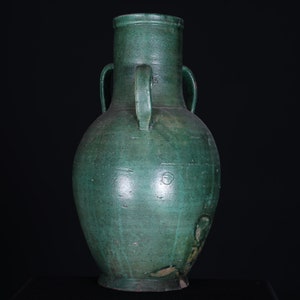 May include: A large, green ceramic vase with two handles. The vase has a rounded body and a narrow neck.