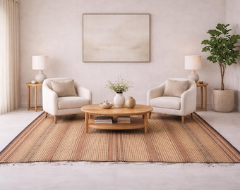 May include: A living room scene featuring two white armchairs with beige cushions, a round wooden coffee table, and a striped rug. Two small side tables with lamps flank the chairs. A large framed artwork hangs on the wall.