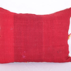May include: A red rectangular pillow with a textured fabric. The pillow has a simple design and is made of a patchwork of different fabrics.