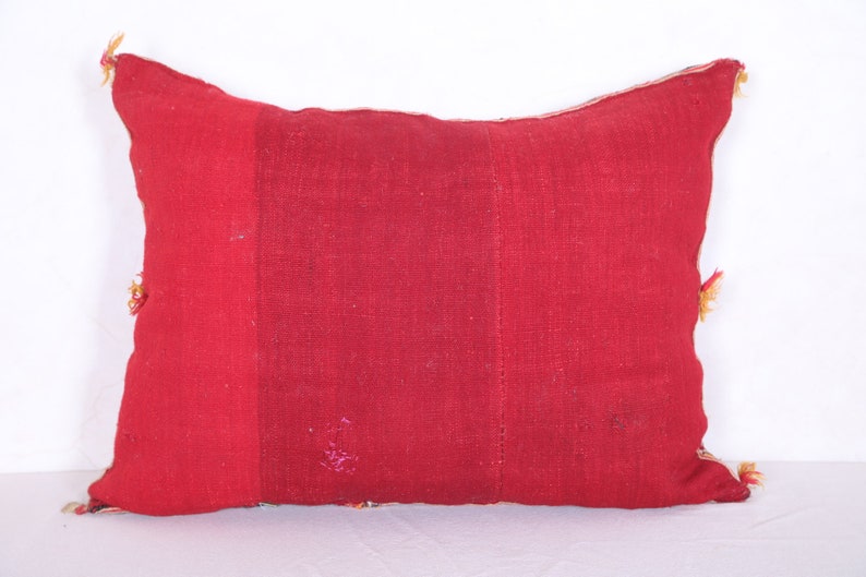 May include: A red rectangular pillow with a textured fabric. The pillow has a simple design and is made of a patchwork of different fabrics.