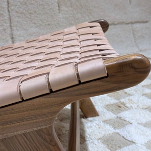 May include: A wooden chair with a woven leather seat. The chair has a dark brown finish and the leather is a light brown colour.