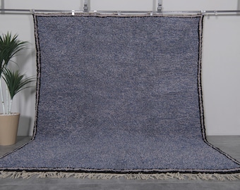 May include: A large, blue, hand-woven rug with a fringe border. The rug has a subtle, textured pattern and is made of wool.