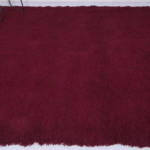 May include: A deep burgundy shag rug with a fringe border.
