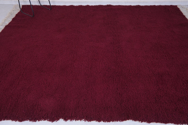 May include: A deep burgundy shag rug with a fringe border.