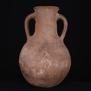 Puede incluir: Una jarra de cer&aacute;mica de terracota marr&oacute;n con dos asas. La jarra tiene un cuerpo redondeado y un cuello estrecho.