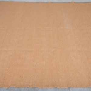 May include: A large, rectangular, brown woven rug with a slightly rough texture.