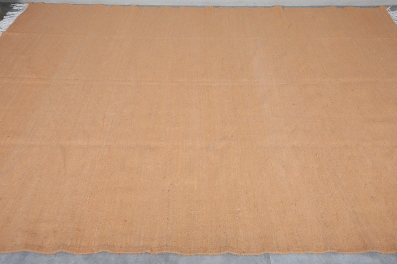 May include: A large, rectangular, brown woven rug with a slightly rough texture.