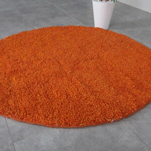 May include: A round, orange, fluffy rug with a soft, plush texture.