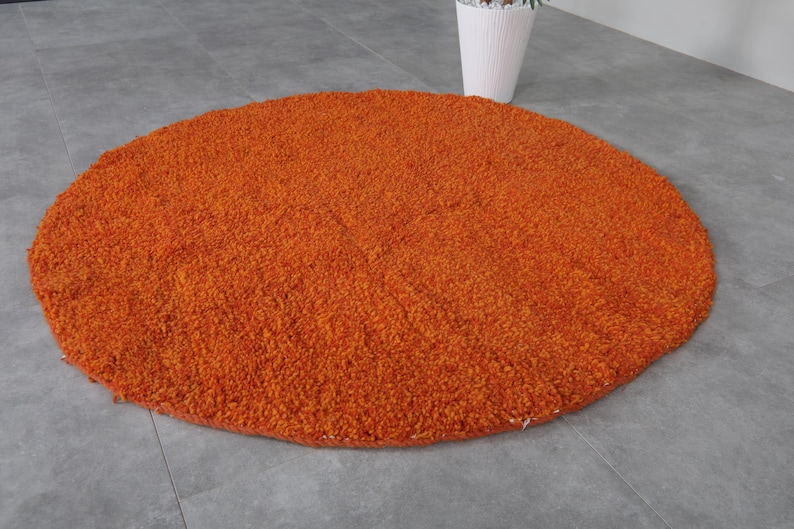 May include: A round, orange, fluffy rug with a soft, plush texture.