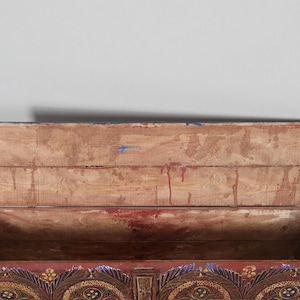 May include: An antique wooden chest with the lid open, revealing the interior. The chest is painted in shades of red, gold, and blue, with ornate floral and geometric designs. The interior is made of light-coloured wood.