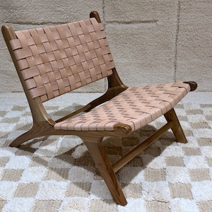 May include: A brown leather chair with a woven leather seat and back. The chair has a simple, modern design and is made of natural materials.