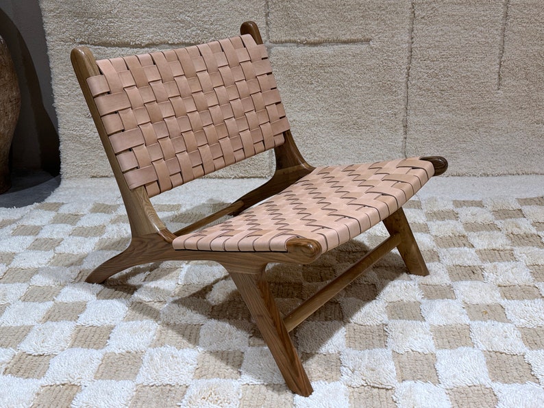 May include: A brown leather chair with a woven leather seat and back. The chair has a simple, modern design and is made of natural materials.