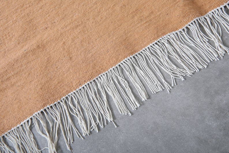 May include: A brown woven rug with white fringe along the edge.