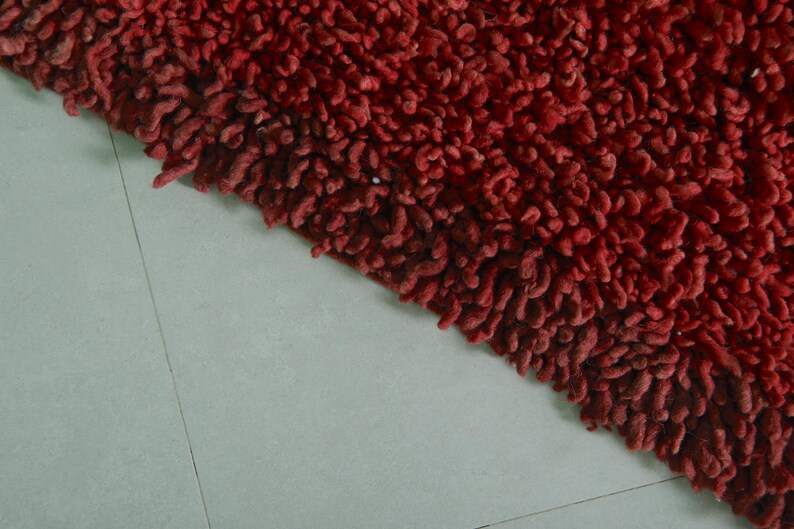 May include: Close-up of a red shaggy bath mat with a textured surface.