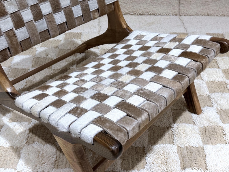 May include: A woven leather chair with a chequered pattern in shades of brown and white. The chair is made of wood and has a simple, modern design.