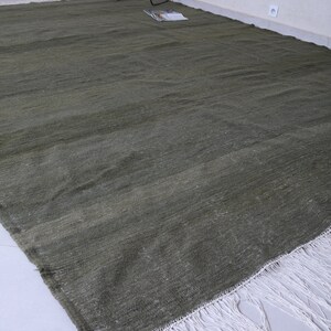 May include: A green rug with a white fringe. The rug is made of a soft, woven material and has a subtle texture.