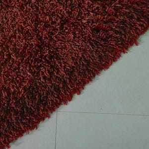 May include: Close-up of a deep red shaggy rug with a soft, fluffy texture.