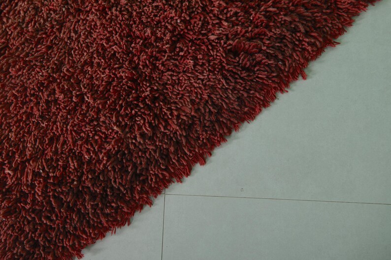 May include: Close-up of a deep red shaggy rug with a soft, fluffy texture.