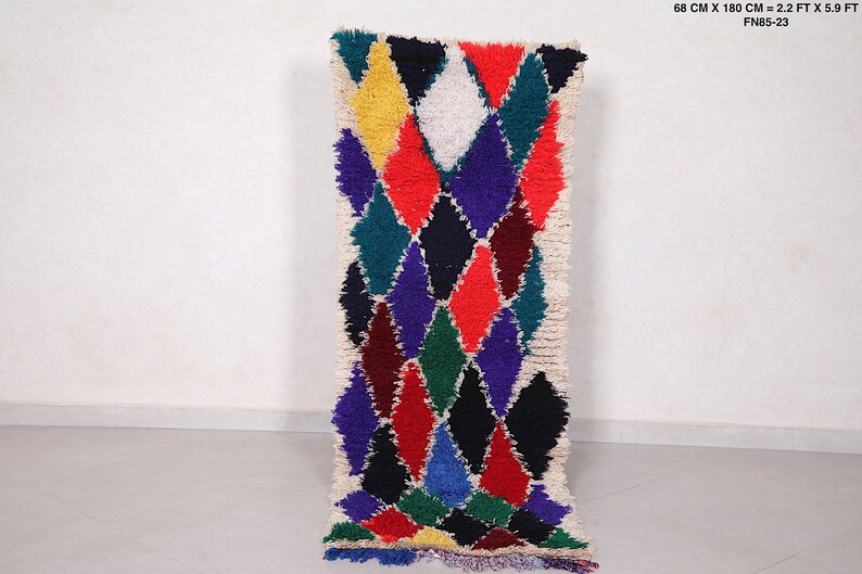 May include: A long, narrow rug with a white background and a colorful diamond pattern. The diamonds are in shades of red, blue, green, yellow, and black. The rug is 68 cm x 180 cm, or 2.2 ft x 5.9 ft.
