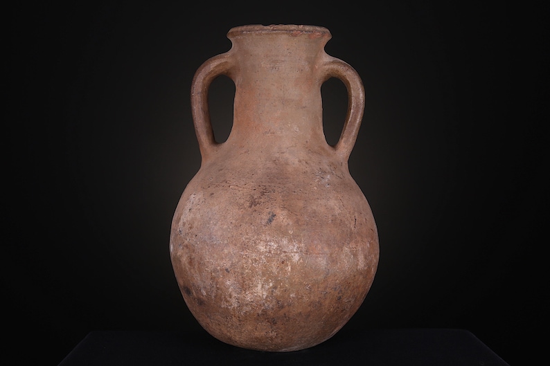 Puede incluir: Una &aacute;nfora de terracota marr&oacute;n con dos asas. La &aacute;nfora es una jarra grande de cuerpo redondo con cuello estrecho.
