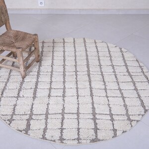 May include: A round, white and gray area rug with a geometric pattern. A wooden chair sits on the rug.