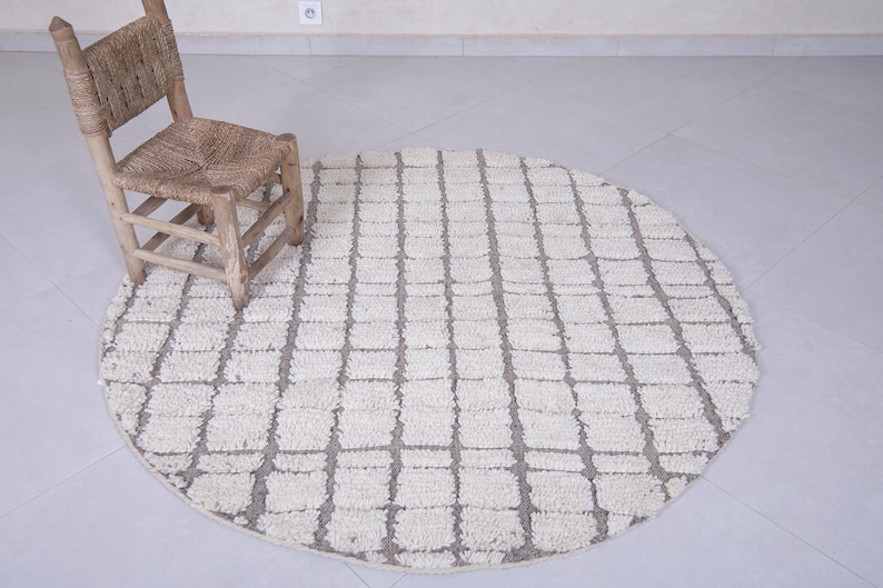 May include: A round, white and gray area rug with a geometric pattern. A wooden chair sits on the rug.