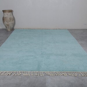 May include: A light blue shag rug with a fringe border. The rug is on a gray tiled floor.