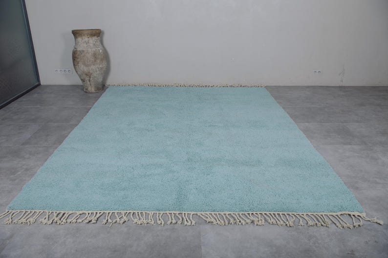 May include: A light blue shag rug with a fringe border. The rug is on a gray tiled floor.