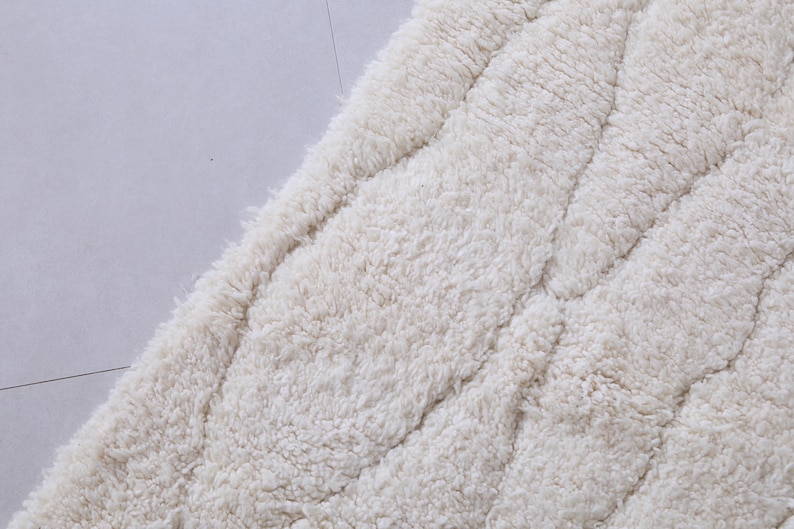 May include: A close-up of a white, fluffy, textured rug with a quilted pattern.