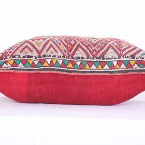 May include: A red and white patterned pillow with a geometric design. The pillow is made of a soft, woven fabric and has a fringed edge.