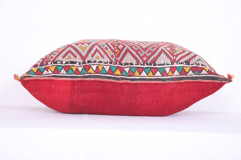 May include: A red and white patterned pillow with a geometric design. The pillow is made of a soft, woven fabric and has a fringed edge.