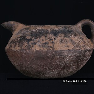 May include: A brown, round, ceramic jug with a handle and a spout. The jug is 10.2 inches wide and 5.9 inches tall.
