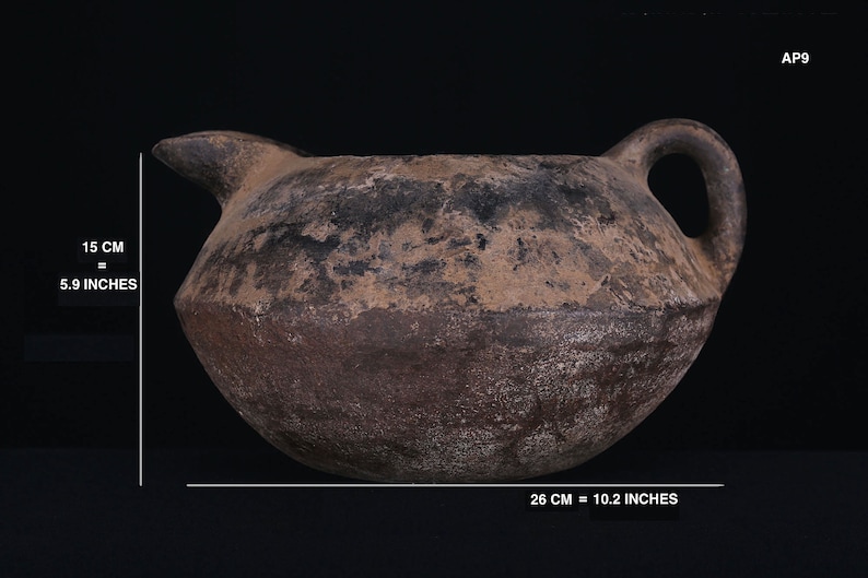 May include: A brown, round, ceramic jug with a handle and a spout. The jug is 10.2 inches wide and 5.9 inches tall.