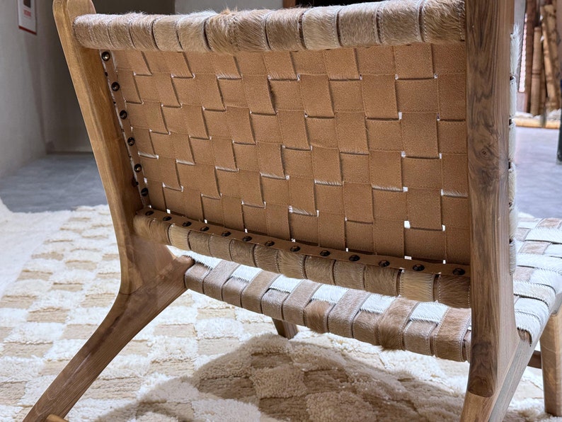 May include: A wooden chair with a woven leather seat and back. The chair has a natural wood finish and the leather is a light brown colour.