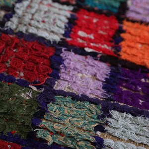 May include: A colorful patchwork rug with squares of different colors and textures, including red, green, purple, orange, and white.
