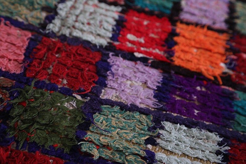 May include: A colorful patchwork rug with squares of different colors and textures, including red, green, purple, orange, and white.