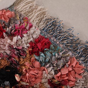 Puede incluir: Una alfombra colorida hecha de retazos de tela, con una variedad de texturas y patrones. La alfombra tiene un borde de flecos y est&aacute; hecha en estilo patchwork.
