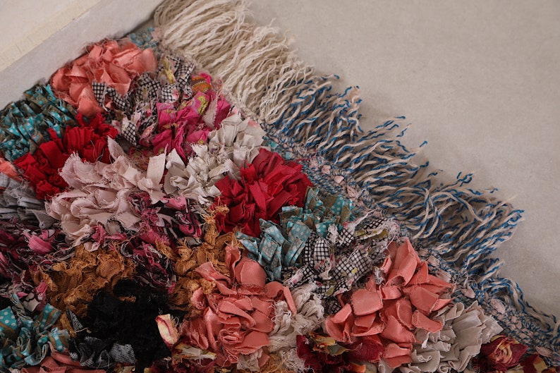Puede incluir: Una alfombra colorida hecha de retazos de tela, con una variedad de texturas y patrones. La alfombra tiene un borde de flecos y est&aacute; hecha en estilo patchwork.