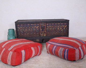 May include: Two red and white striped floor cushions with a decorative wooden chest with colorful geometric patterns in the background.