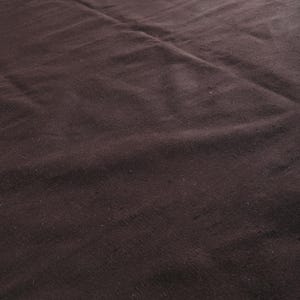 Może przedstawiać: Ciemnobrązowy dywan o lekko fakturowanej powierzchni. Dywan jest złożony na środku, tworząc fałdę.