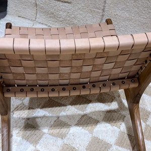 May include: A brown wooden chair with a woven leather seat and back. The chair has a simple design with a curved back and legs.