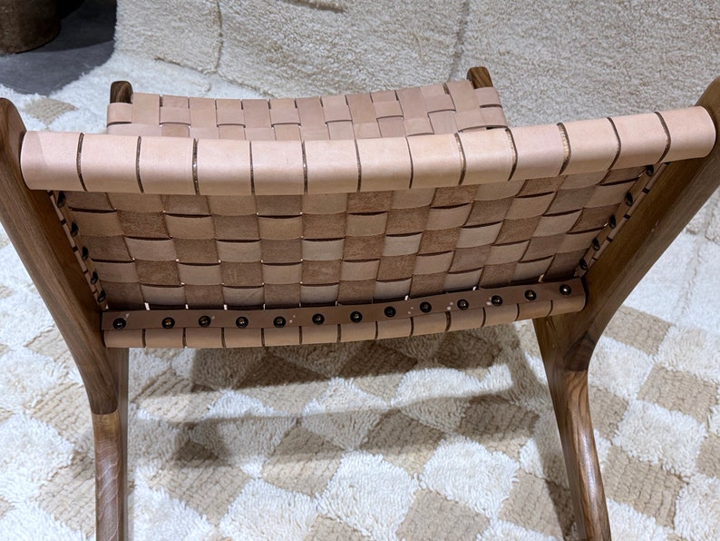 May include: A brown wooden chair with a woven leather seat and back. The chair has a simple design with a curved back and legs.