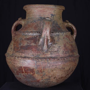 Peut inclure: Un grand pot rond en terre cuite avec deux anses de chaque côté. Le pot est de couleur brun rougeâtre avec une surface rugueuse et texturée.