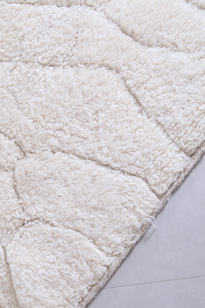 May include: A close-up of a white, fluffy bath mat with a textured, wave-like pattern. The mat has a soft, plush feel and is perfect for adding comfort and style to any bathroom.