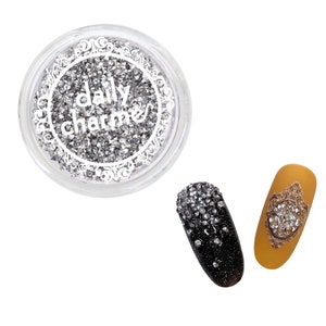 May include: A clear jar filled with silver nail art rhinestones, with the text "daily charme". Two nail art designs are shown: one black with rhinestones, and one mustard yellow with a rhinestone design.