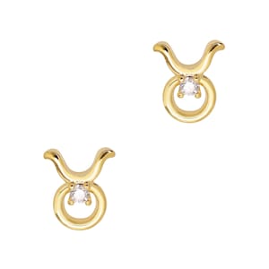 May include: A pair of gold-tone Taurus zodiac sign earrings with a clear crystal stone in the center of each earring.