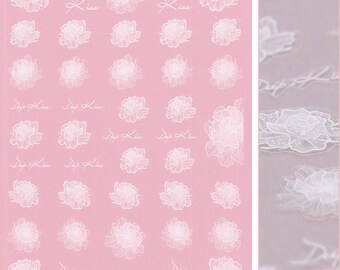 May include: A sheet of white nail decals with a pink background. The decals feature a floral design with the text "Drip Kiss" repeated throughout.