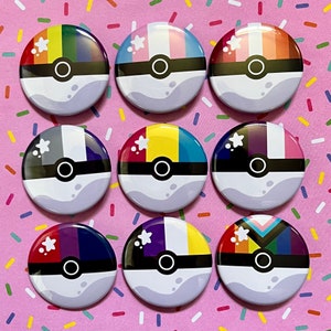 May include: Nine round, white, button badges with different coloured stripes and a black and white pokeball design. Each badge has a white star in the top left corner.