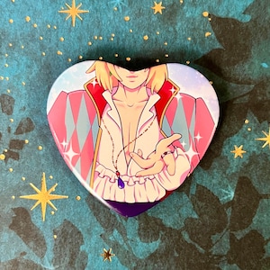 May include: A heart-shaped pin featuring a character with blonde hair wearing a pink and white patterned shirt with a blue pendant necklace. The character is holding out their hand with a ring on their finger.