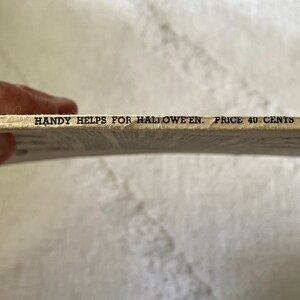 May include: Close-up of the bottom edge of a vintage book with the text "HANDY HELPS FOR HALLOWEEN. PRICE 40 CENTS."